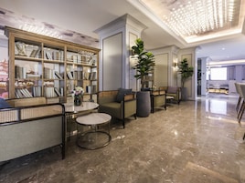 Um hall moderno com piso de mármore, estante de livros, área de estar e um candelabro.