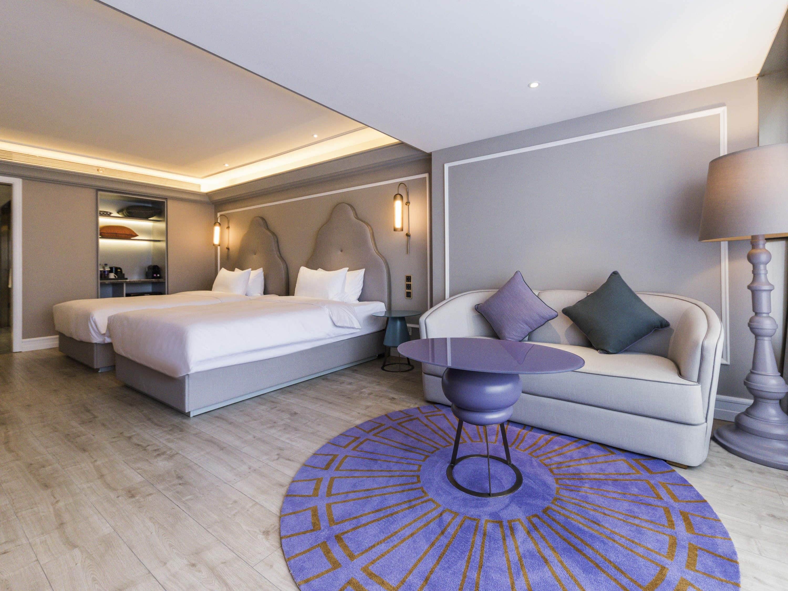Una camera d'albergo con un letto, un divano, un tavolino e un tappeto decorato.