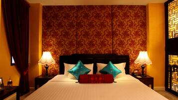 Une chambre d’hôtel avec un grand lit, deux tables de chevet, un rideau rouge et un papier peint à motifs.