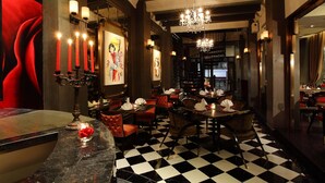 A restaurant with a black and white checkered floor, red upholstered chairs, and a chandelier.