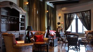 A spacious living room with a large wooden cabinet, multiple armchairs, and a sofa.
