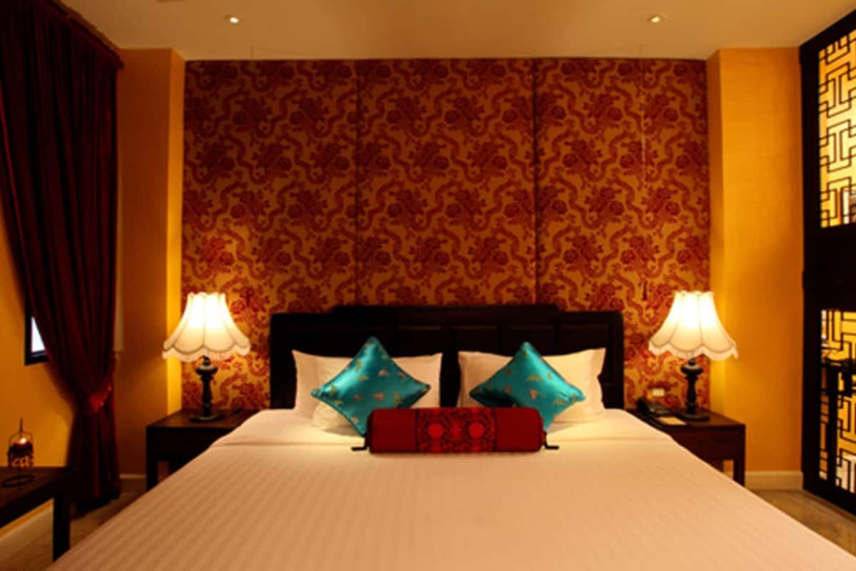 Quarto de hotel com uma cama grande, duas mesas de cabeceira com abajures, papel de parede estampado e uma cabeceira decorativa.