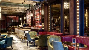 A bar area with leather seating, a checkered floor, and a bar counter with a bartender.