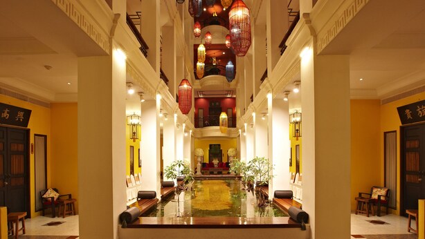 A hotel lobby with a central water feature, seating areas, and traditional lanterns.