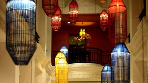 A hotel lobby with multiple levels, ornate railings, and hanging lanterns.