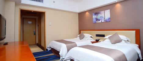 A hotel room with two beds, a wooden desk, and a television.