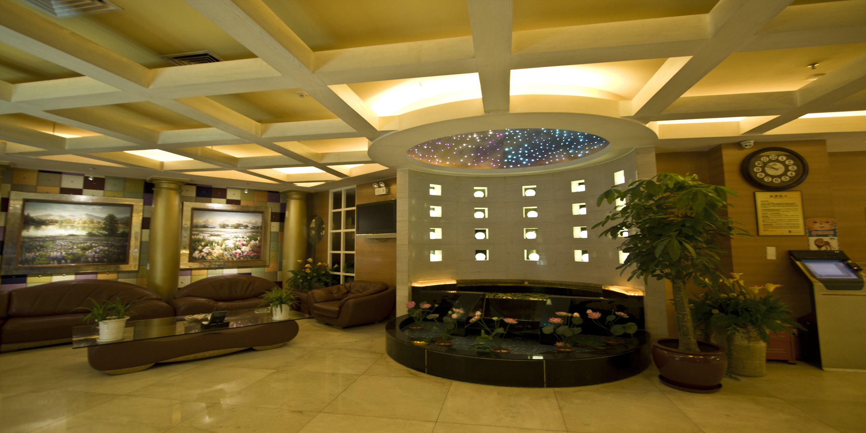 A lobby with a central circular water feature, seating arrangements, and a reception desk.