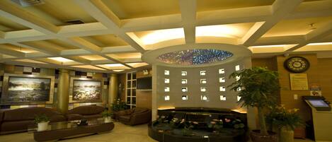 A lobby with a central circular water feature, seating arrangements, and a reception desk.