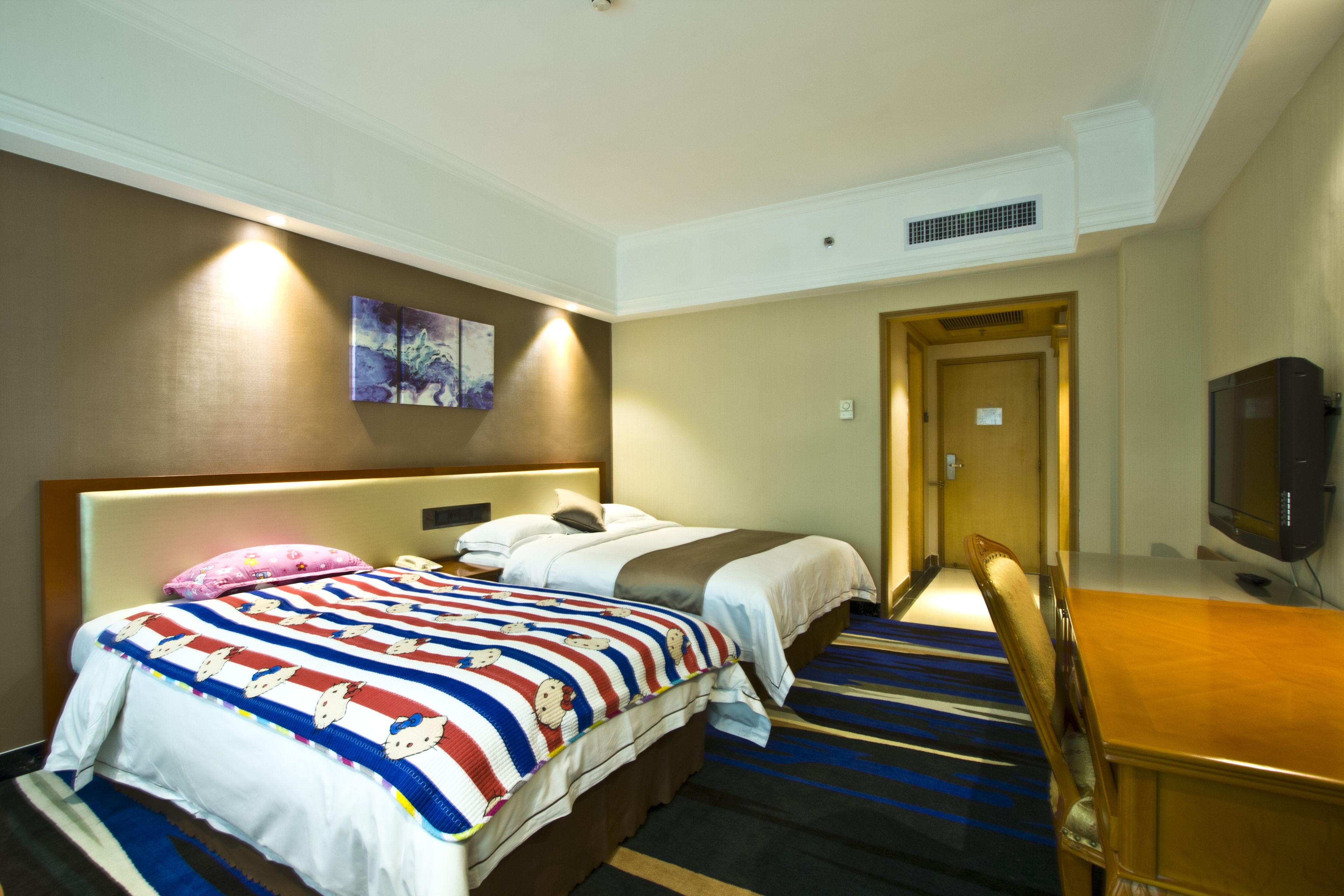 A hotel room with two beds, a desk, a television, and a painting on the wall.