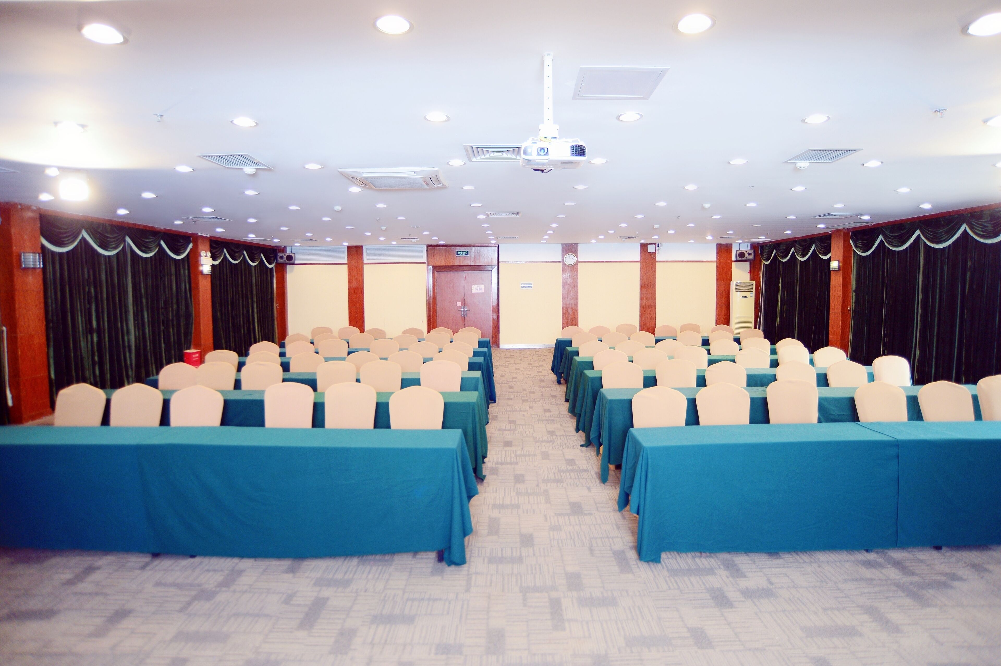 A conference room with rows of tables and chairs, a projector, and a door marked "EXIT".