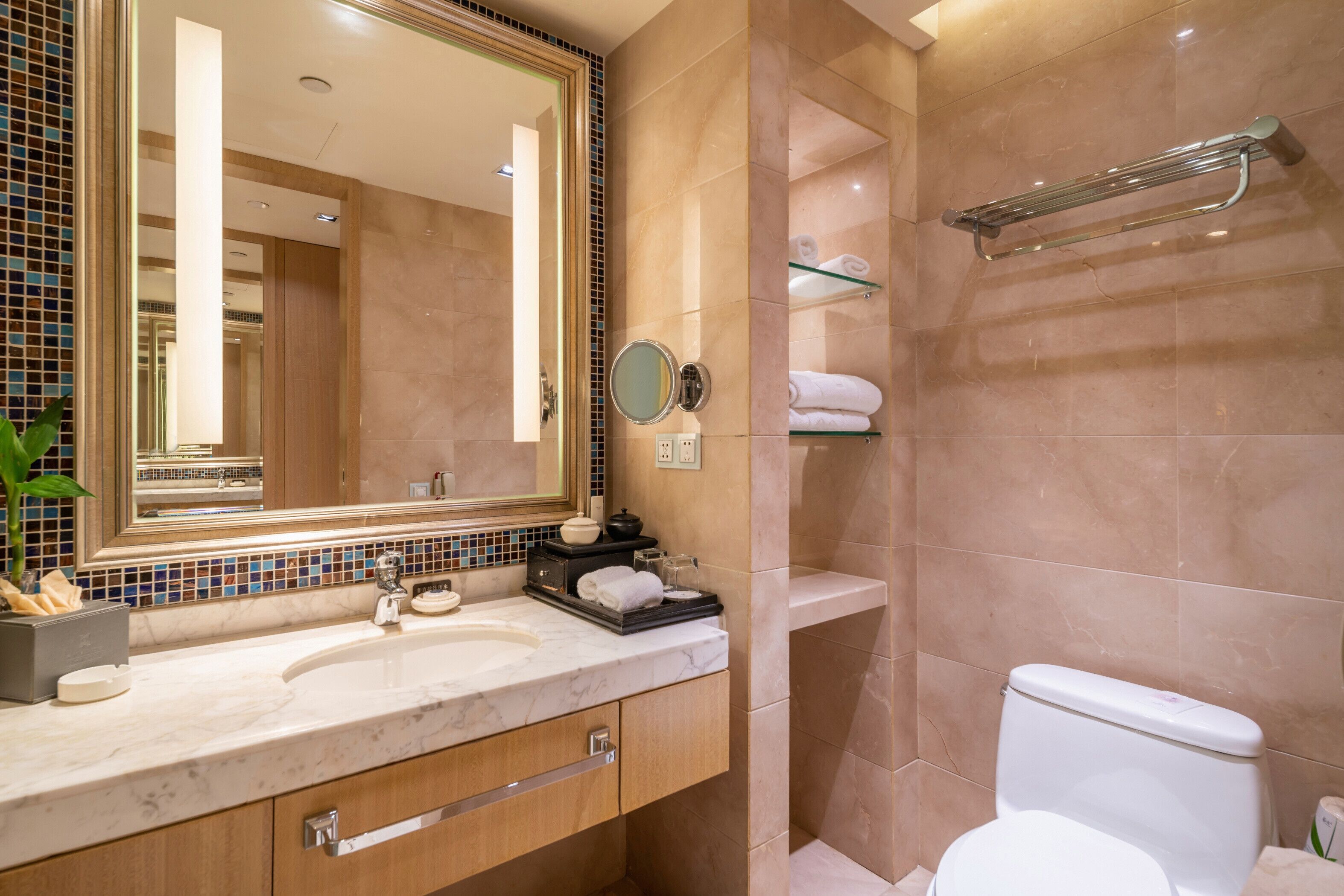 Un baño con lavamanos de mármol, un espejo, toallero y un inodoro.