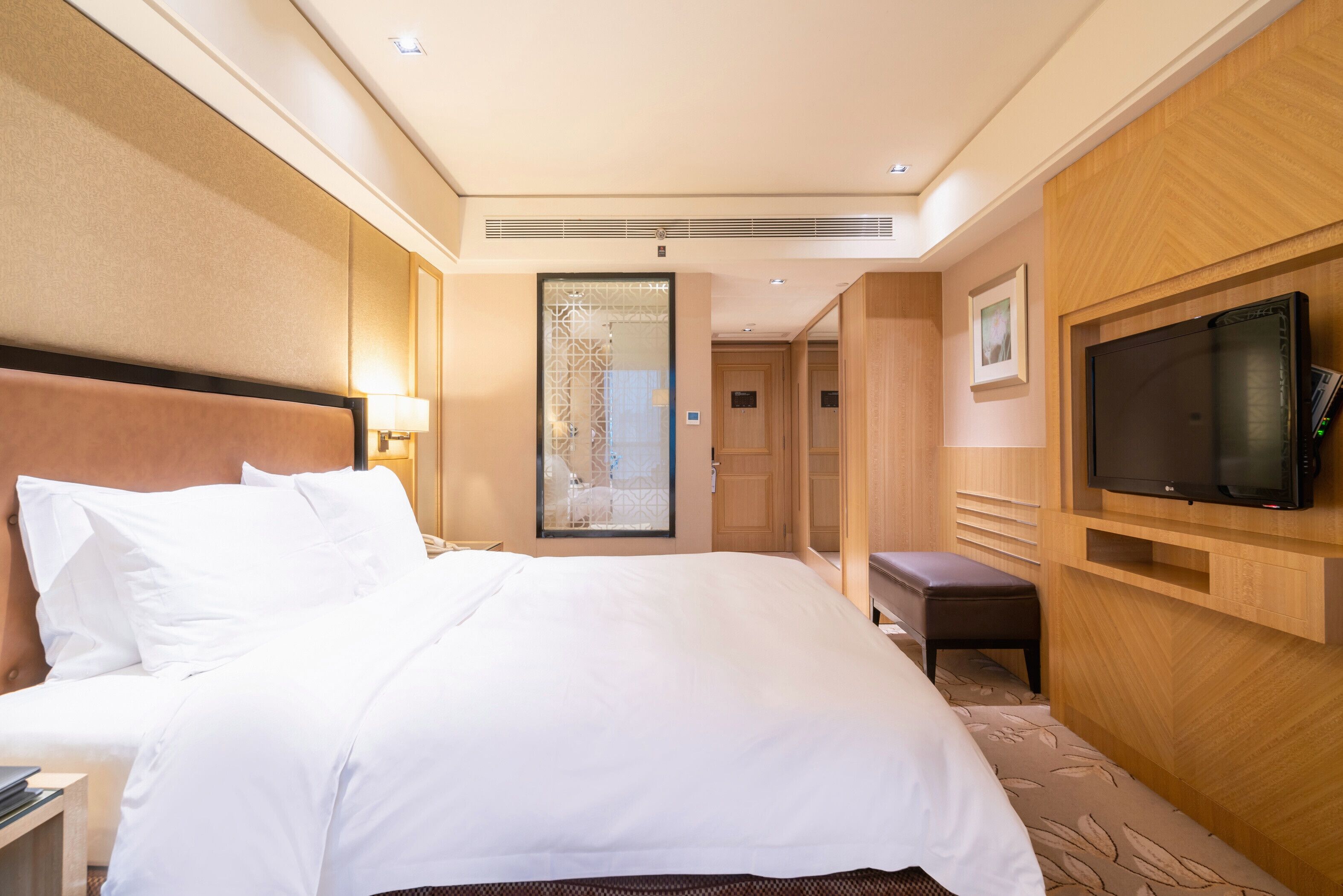 A hotel room with a large bed, a television, and a mirror.