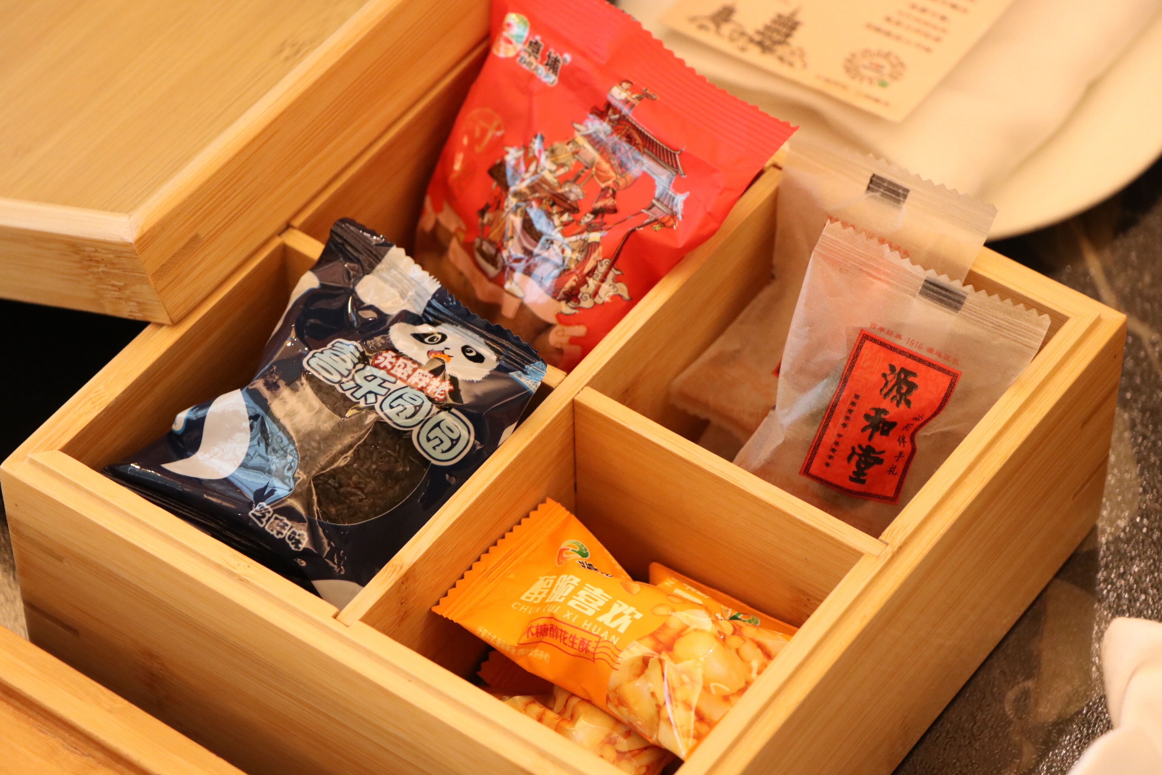 A wooden box containing various packaged food items.