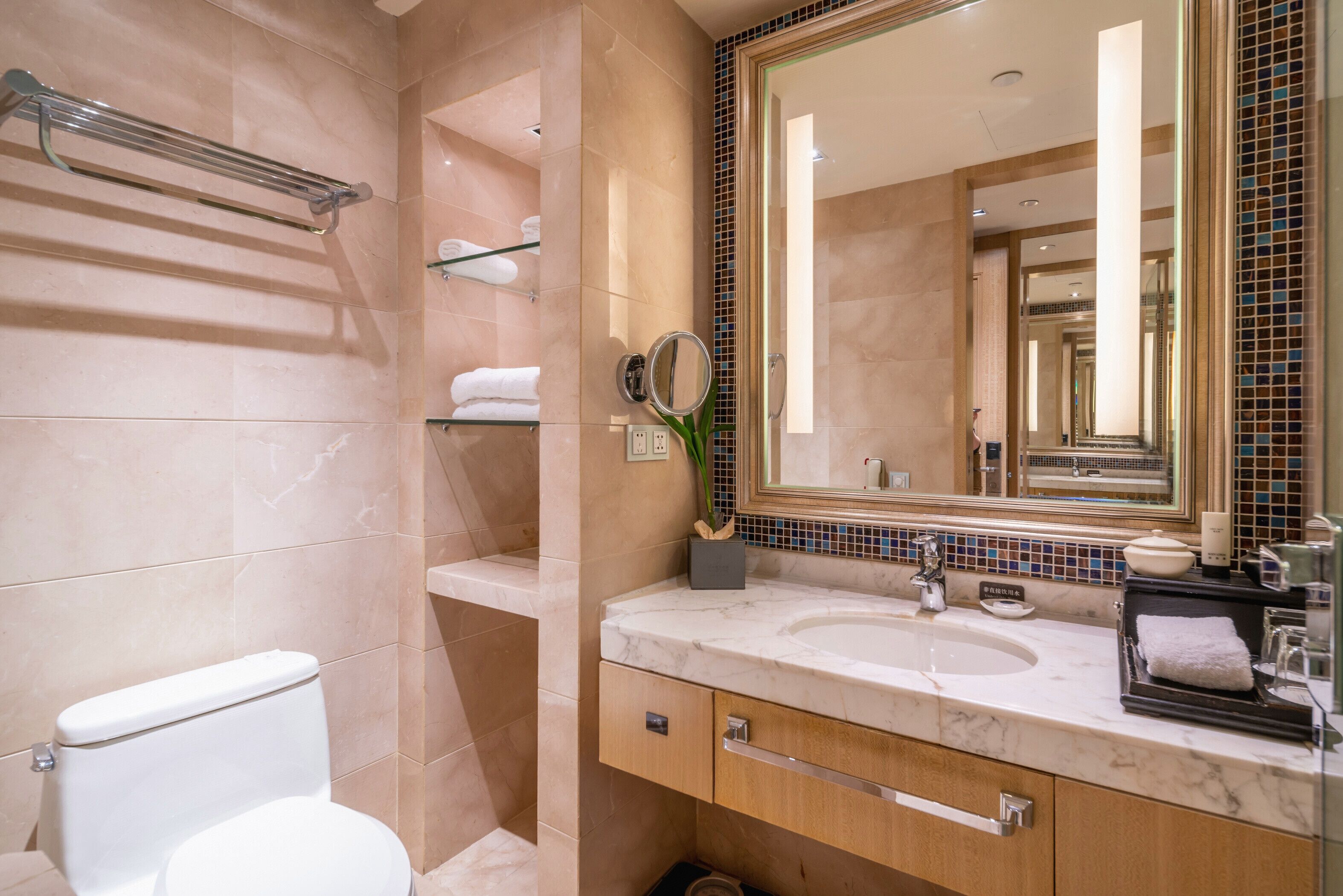 A modern bathroom with a marble sink, a large mirror, and a towel rack.