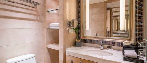 A modern bathroom with a marble sink, a large mirror, and a towel rack.