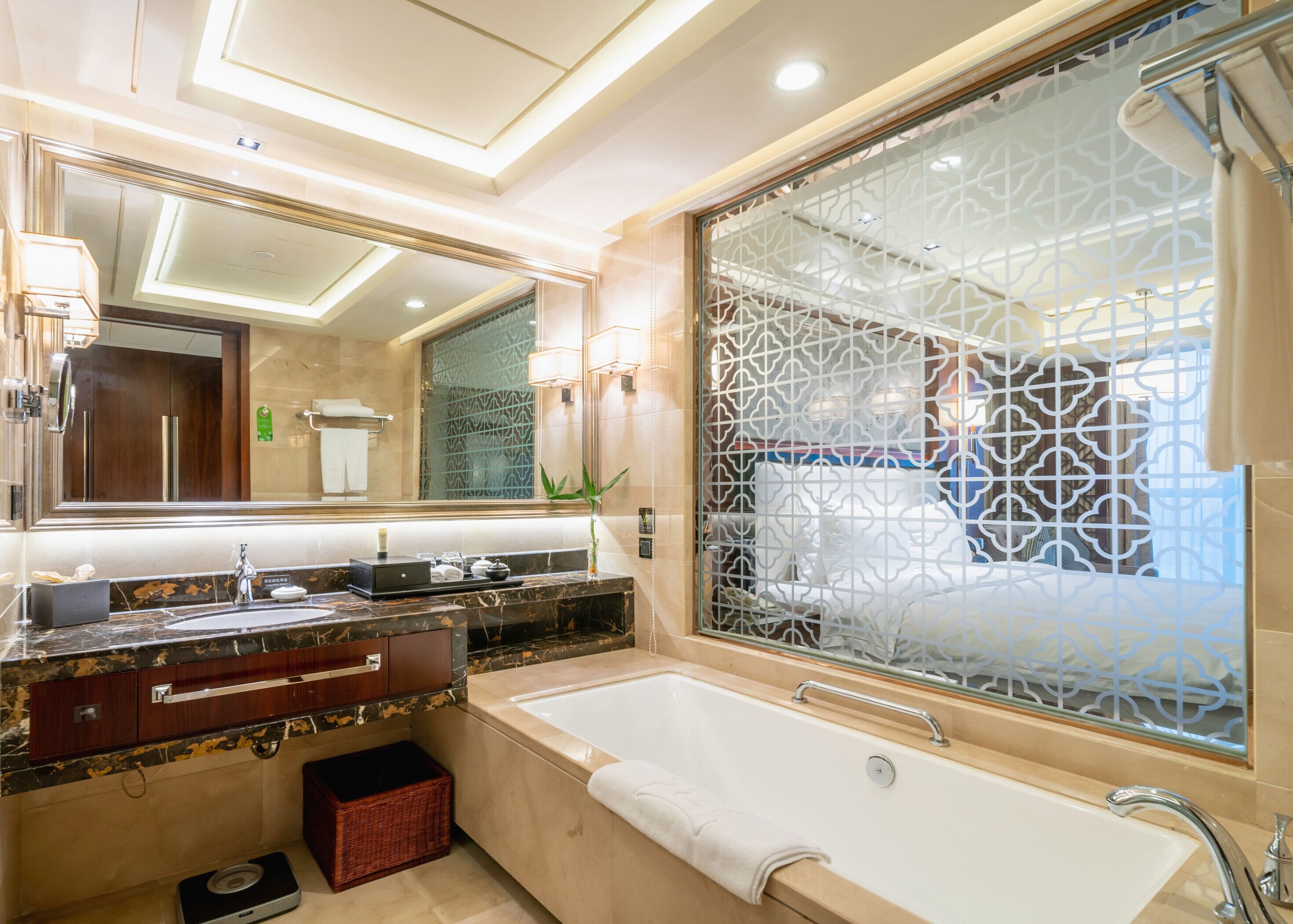 Une salle de bain moderne dotée d’un grand miroir, d’une baignoire et d’un meuble-lavabo avec un plan de travail en marbre.