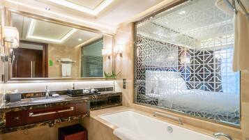 Une salle de bain moderne dotée d’un grand miroir, d’une baignoire et d’un meuble-lavabo avec un plan de travail en marbre.