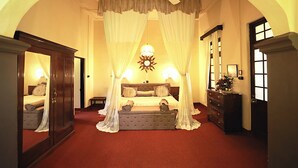 A bedroom with a four-poster bed, a nightstand, a dresser, and a mirror. - Bandarawela Hotel (Bandarawela)