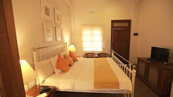A neatly arranged hotel room with a bed, bedside lamps, a television, and a window with blinds.