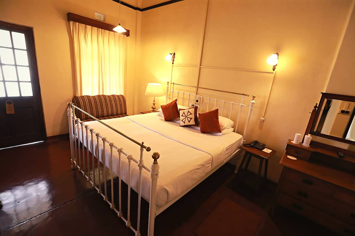 Una habitación de hotel con cama, mesita de noche, lámpara y cómoda.