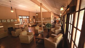 A spacious lobby with wicker furniture, a central table, and framed artwork on the walls. - Bandarawela Hotel (Bandarawela)