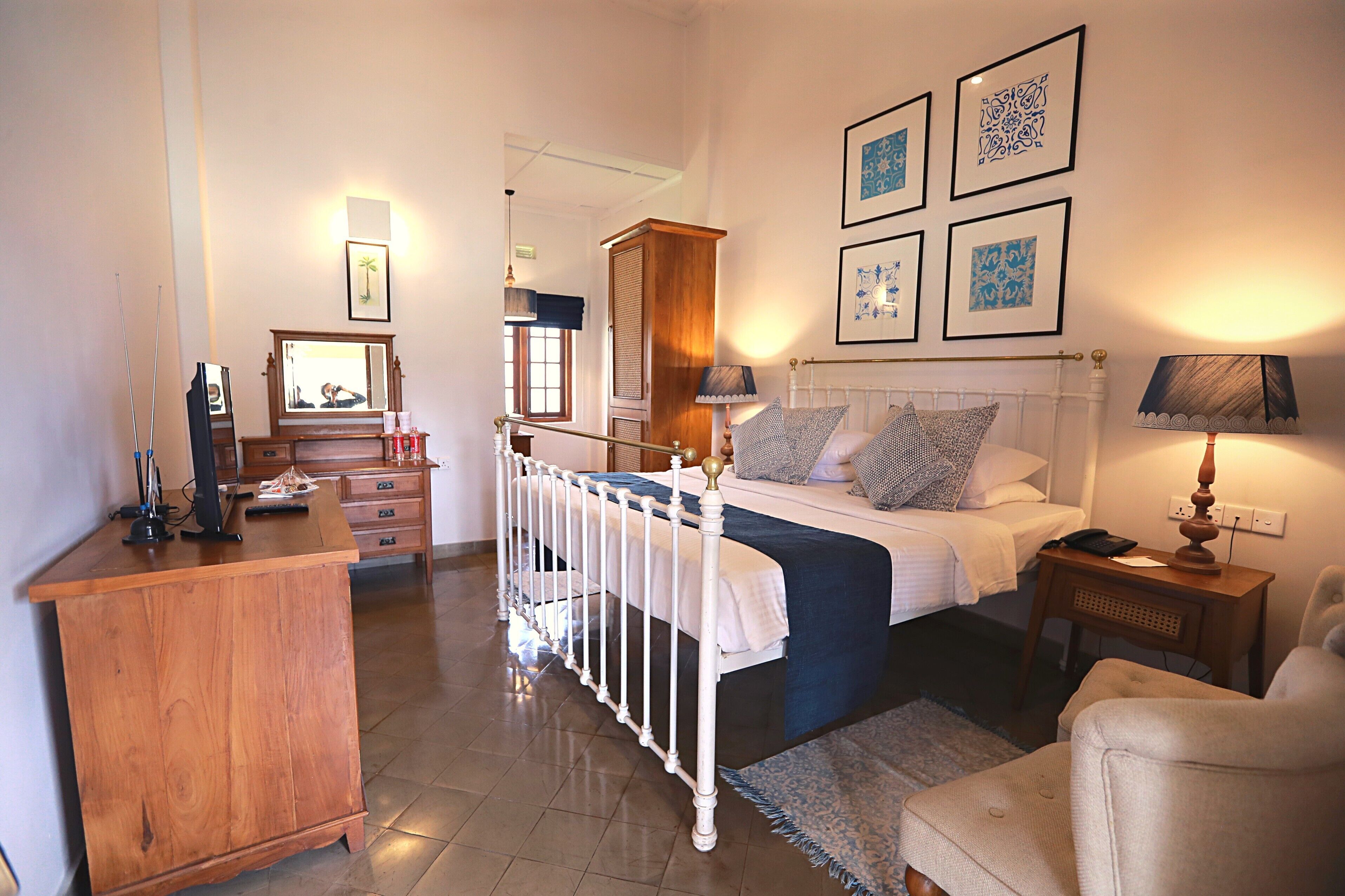 A bedroom with a bed, bedside table, lamp, chair, dresser, and a mirror.