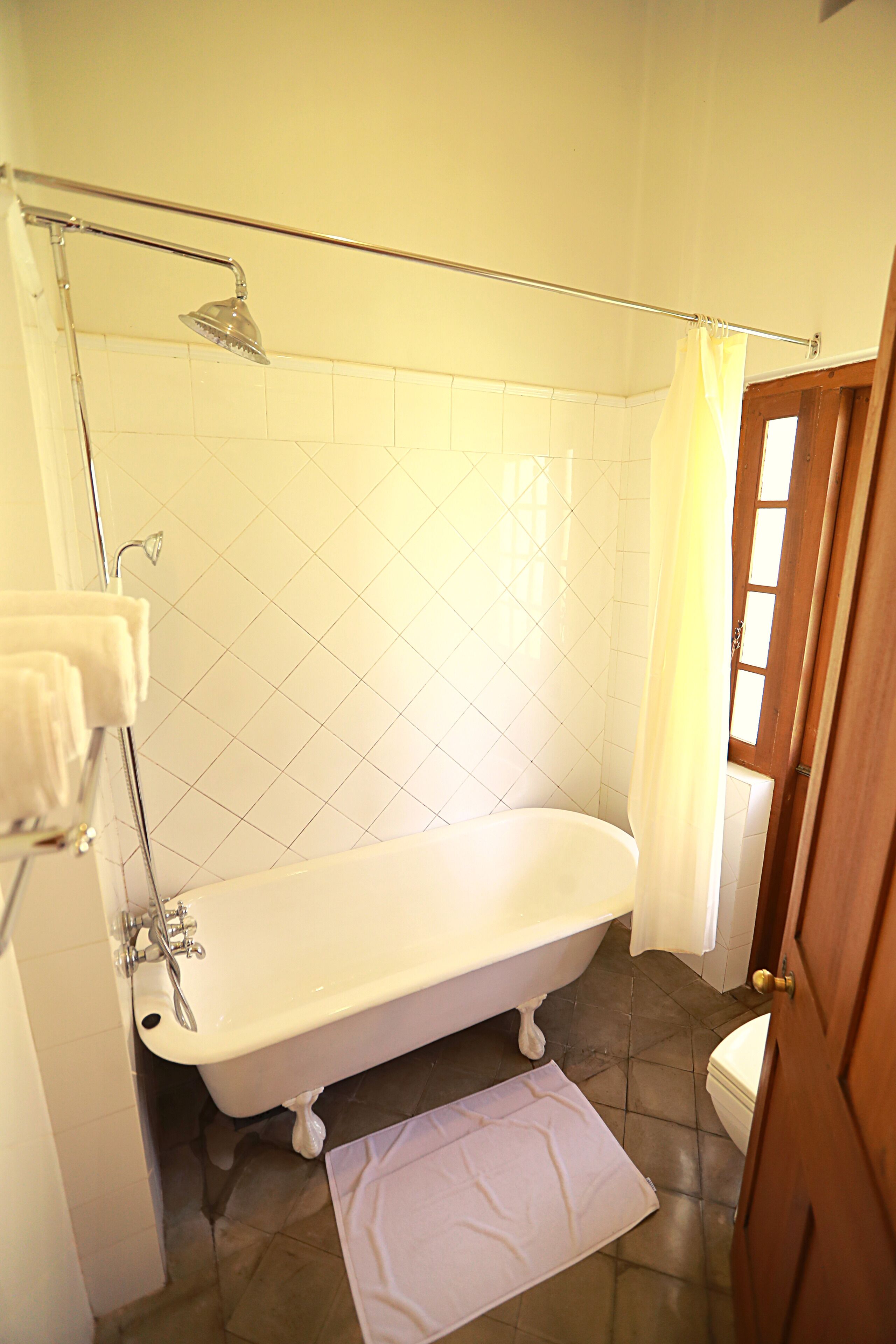 A bathroom with a freestanding bathtub, a showerhead, a toilet, and a door.