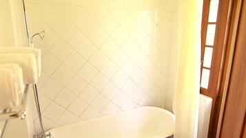 A bathroom with a freestanding bathtub, a showerhead, a toilet, and a door.