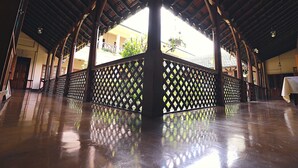 An indoor area with a wooden ceiling and a reflective floor, featuring a central column and a lattice partition. - Bandarawela Hotel (Bandarawela)