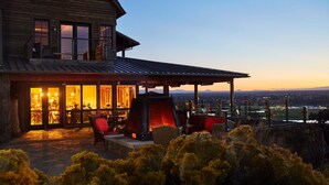 A wooden house with a covered patio, outdoor seating, and a view of the landscape.