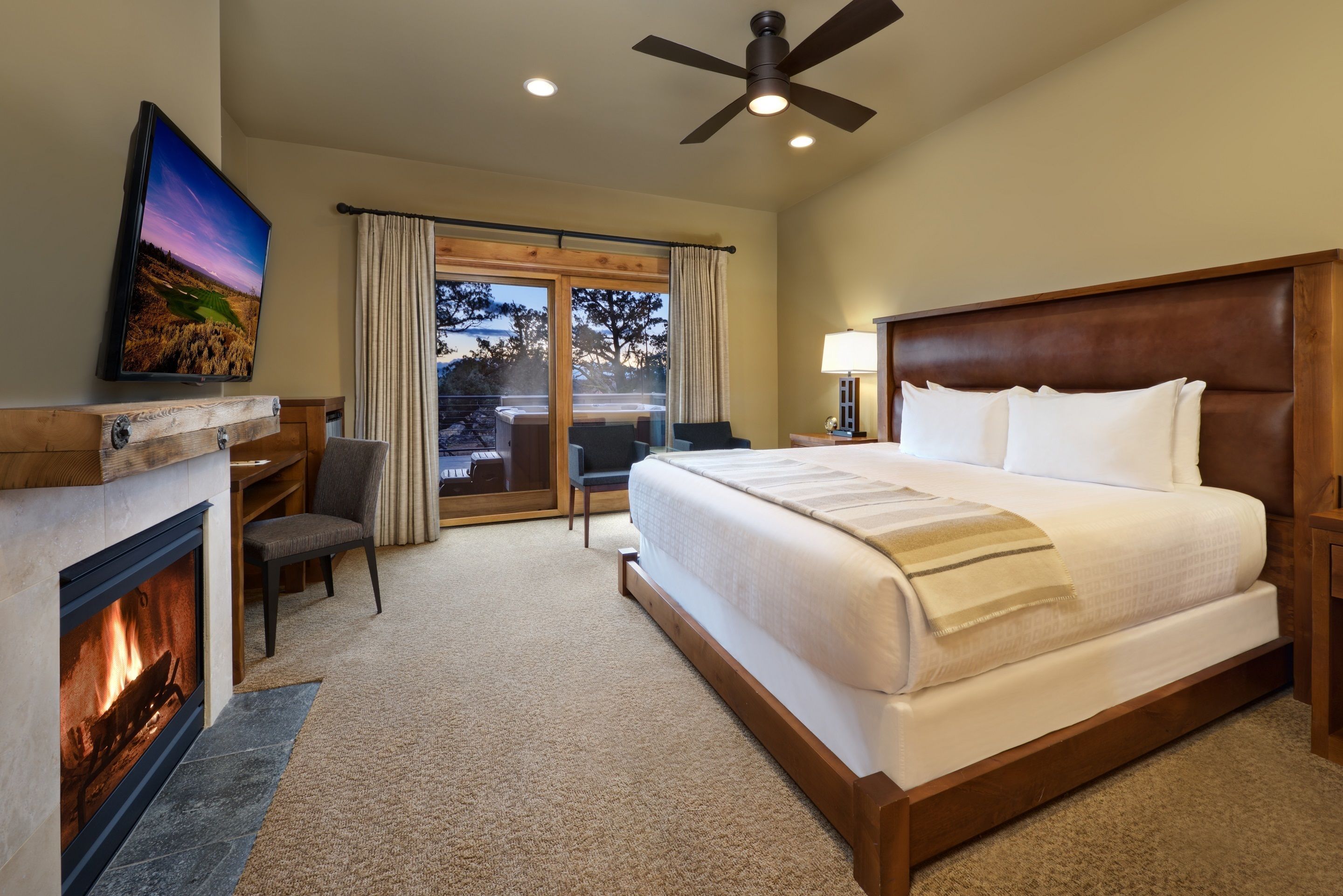 Quarto de hotel com uma cama grande, lareira, televisão e vista para o exterior.