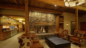 A spacious living area with a stone fireplace, leather sofas, and a bar area with wooden cabinets.