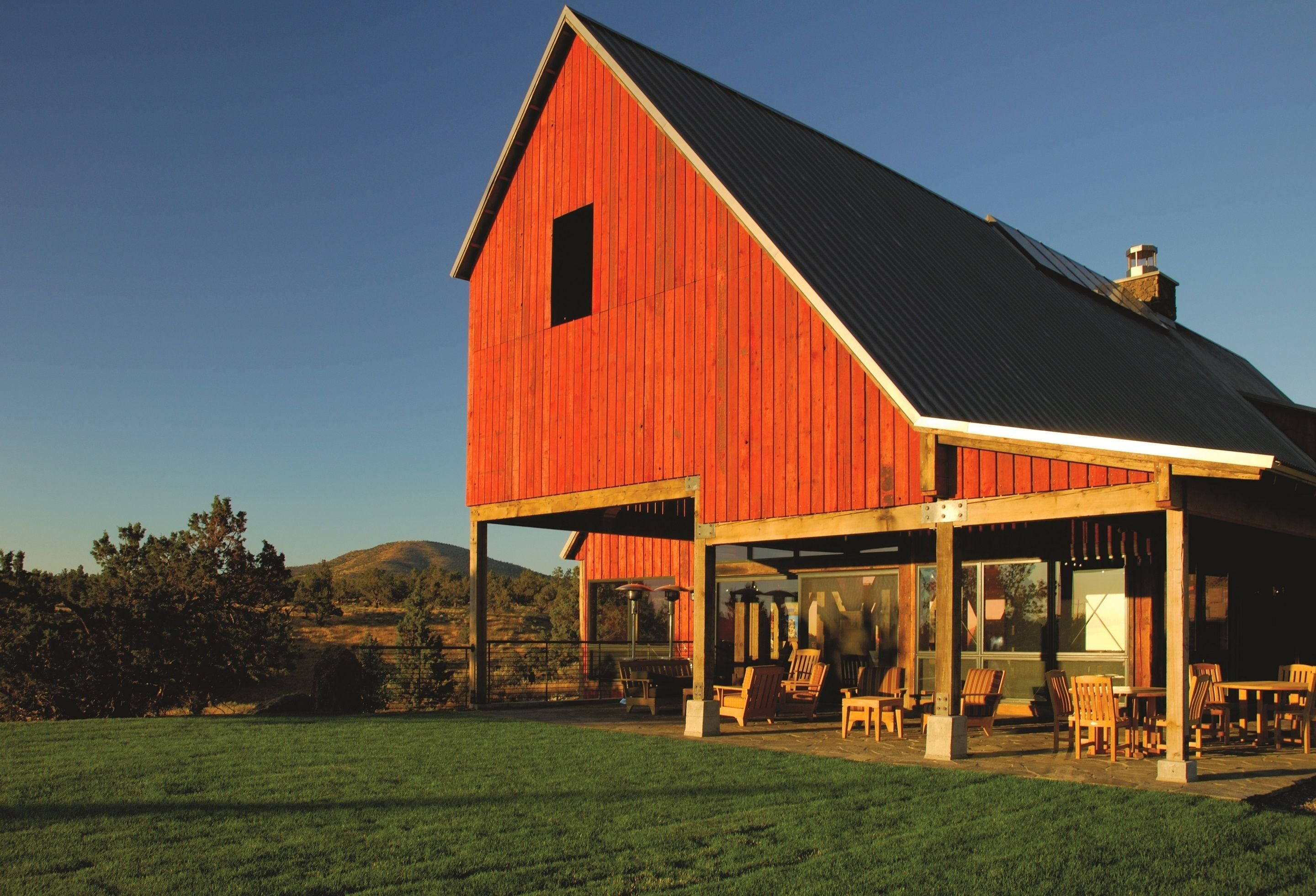 A red barn with a covered patio area and outdoor seating.