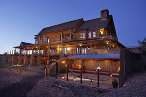 A large, multi-story wooden building with outdoor seating areas and a fire pit.