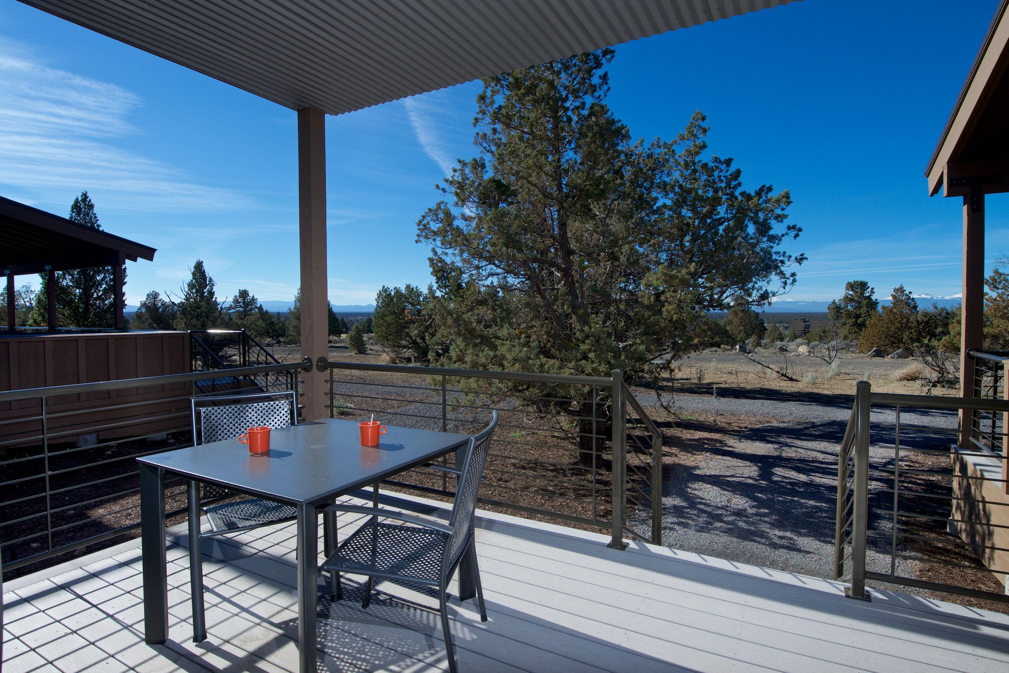 A covered outdoor patio with a table and chairs, overlooking a mountainous landscape.