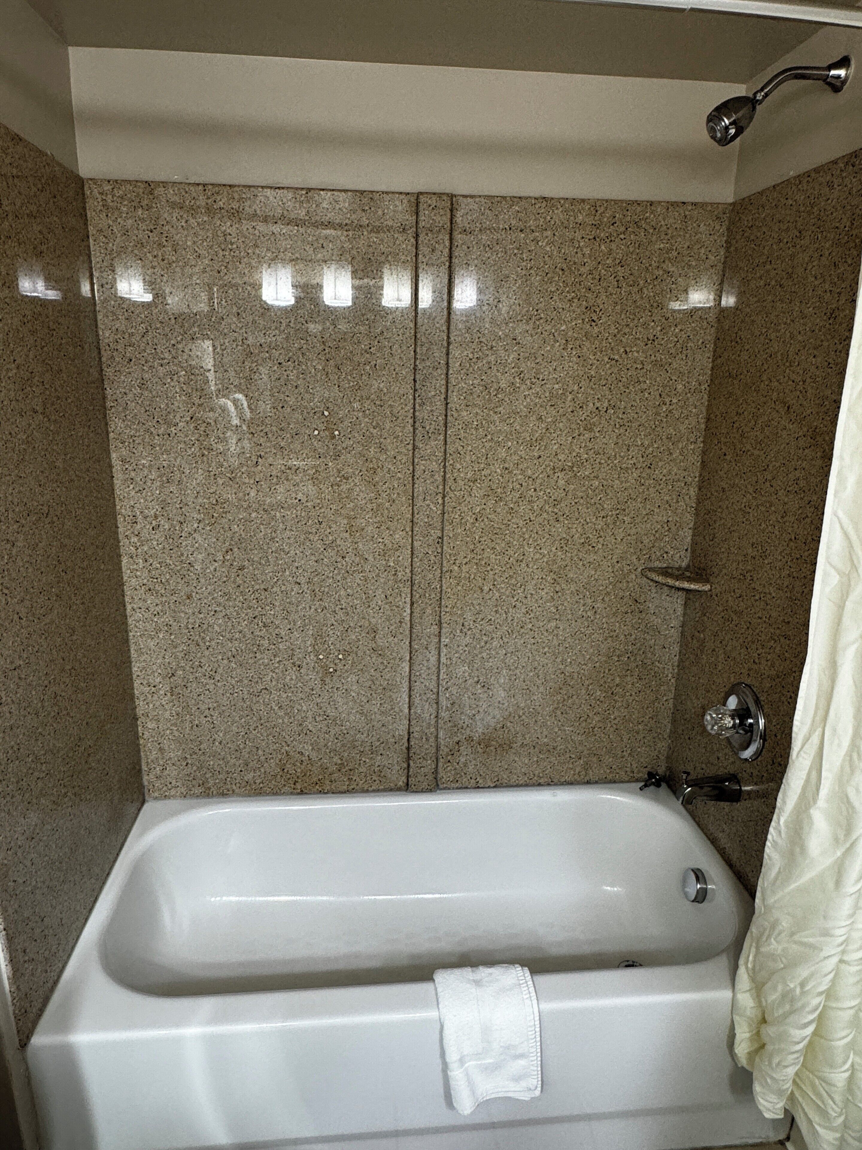 A bathroom with a bathtub, a shower, and a towel hanging on the wall.