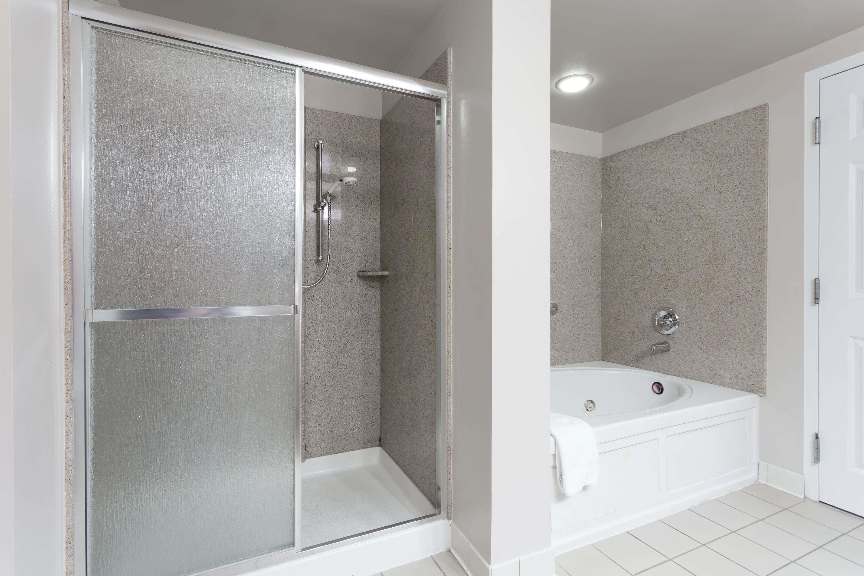 A modern bathroom with a glass-enclosed shower, a freestanding bathtub, and a white tiled floor.