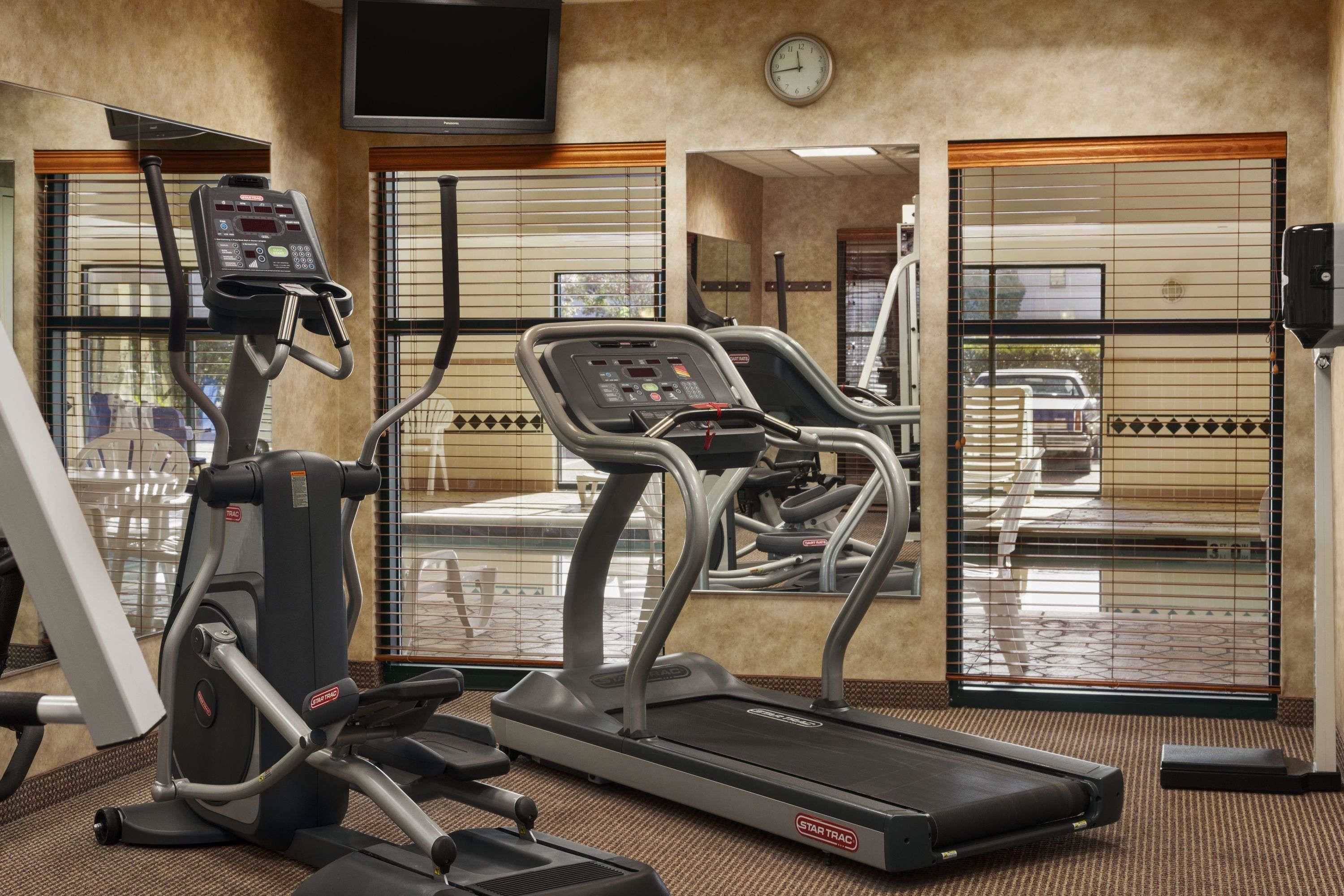 Une salle de sport équipée de tapis de course, d’un vélo elliptique et d’un vélo d’appartement.