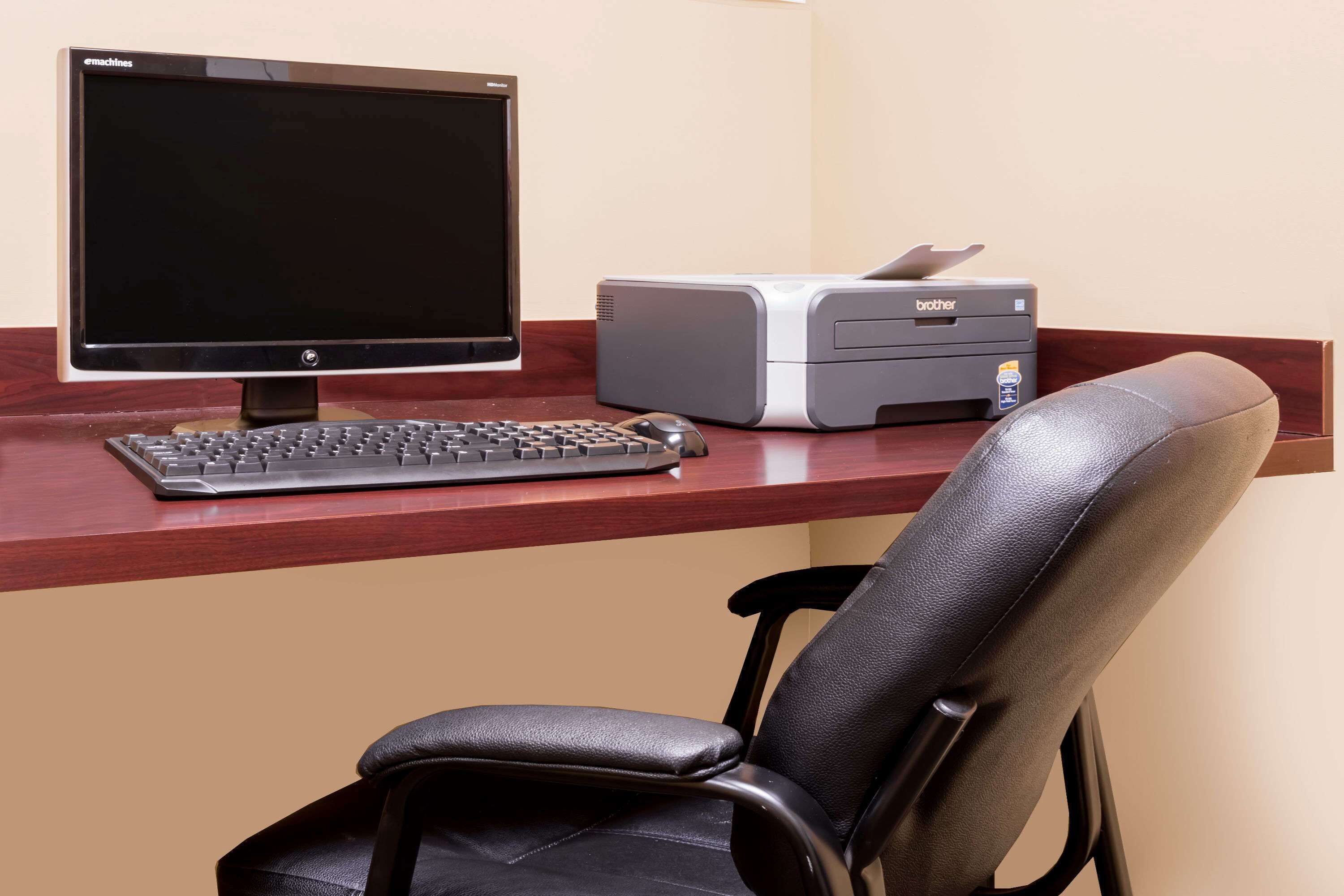 Un escritorio con monitor de computadora, teclado e impresora.