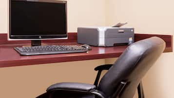 A desk with a computer monitor, keyboard, and printer.