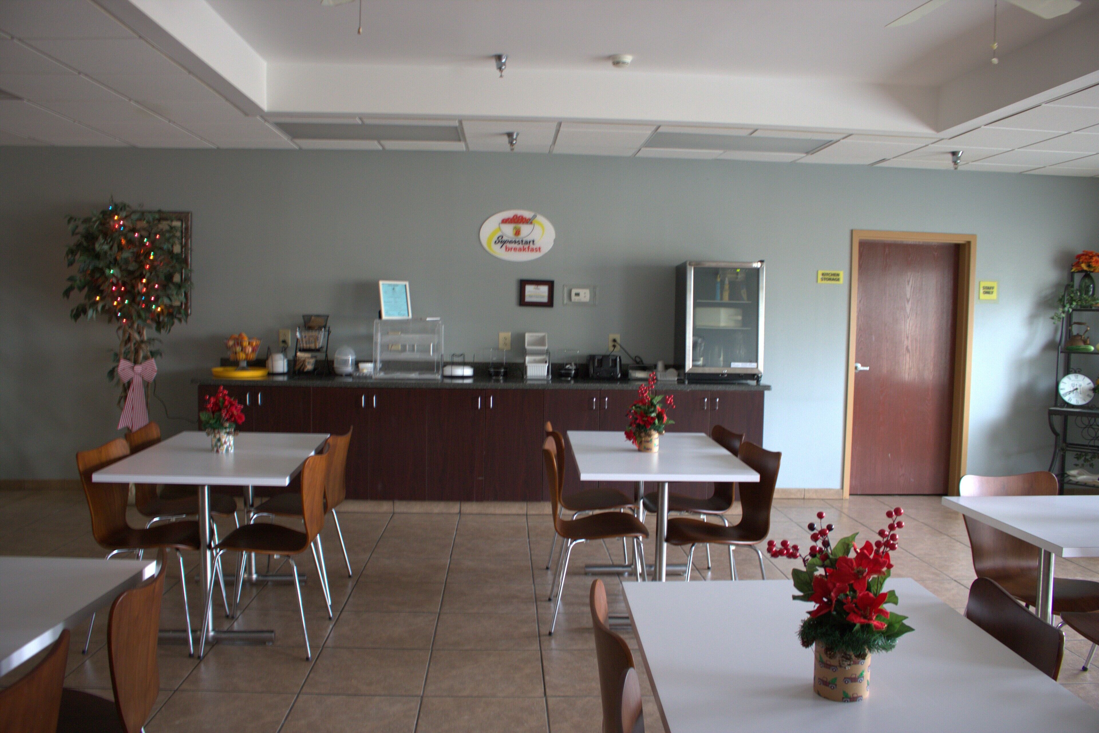A dining area with tables and chairs, a counter with a coffee machine, and a clock on the wall.