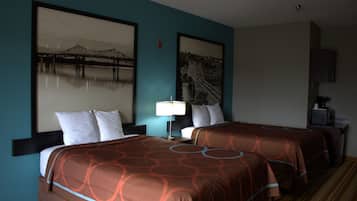 Habitación de hotel con dos camas, una mesita de noche con lámpara y dos cuadros en la pared.