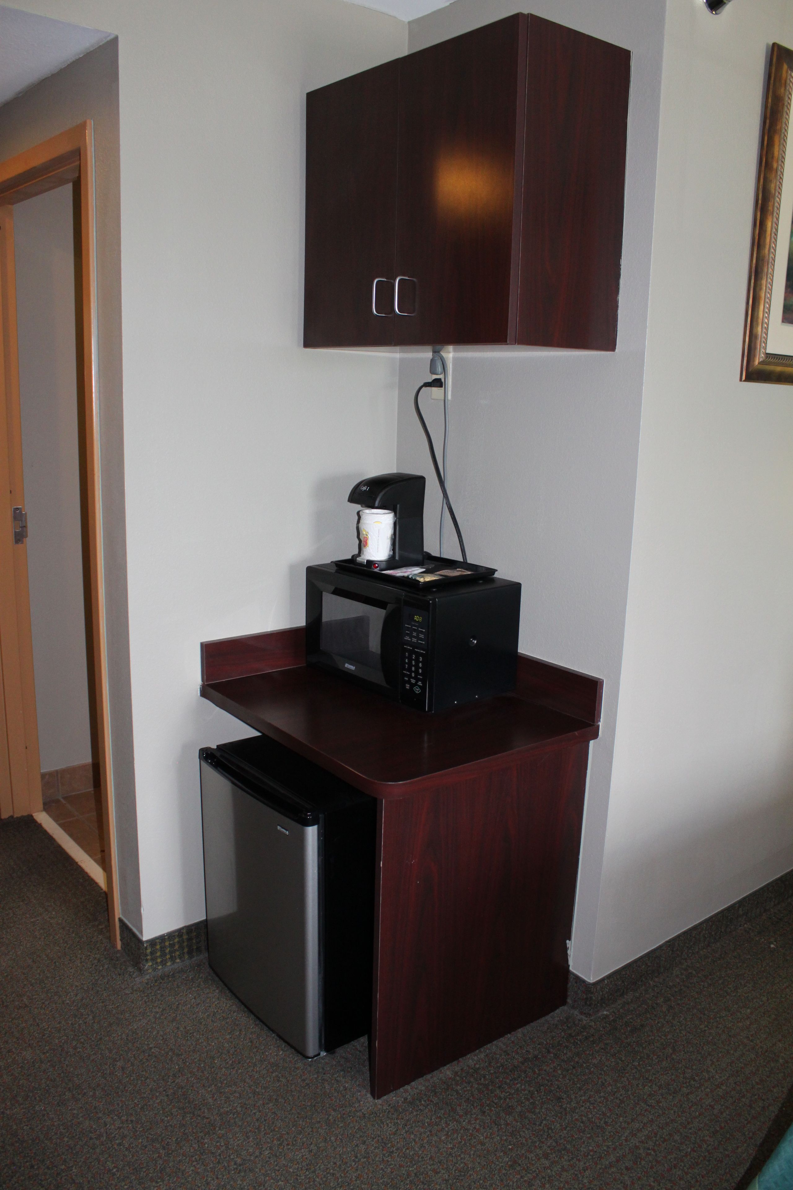 A compact kitchenette with a microwave, coffee maker, and a small refrigerator.