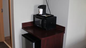 A compact kitchenette with a microwave, coffee maker, and a small refrigerator.