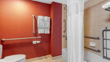 A bathroom with a red wall, a white toilet, a shower with a white curtain, and handrails.