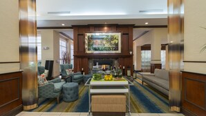 A spacious living room with a fireplace, comfortable seating, and a coffee table with fruit. - Hilton Garden Inn Tupelo (Tupelo)