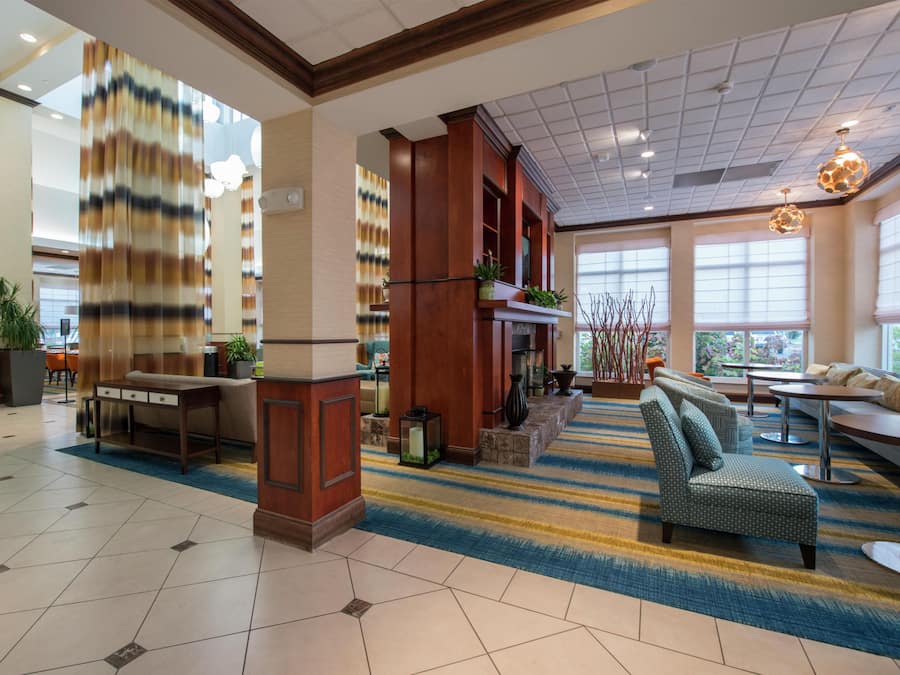 A hotel lobby with a check-in counter, seating area, and large windows.