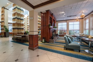 Vestíbulo de hotel con mostrador de recepción, zona de estar y amplias ventanas.