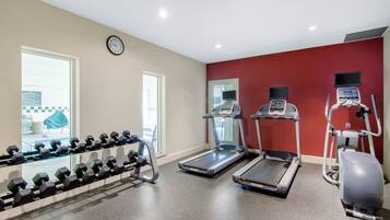 A gym with treadmills, an elliptical, and a set of dumbbells.