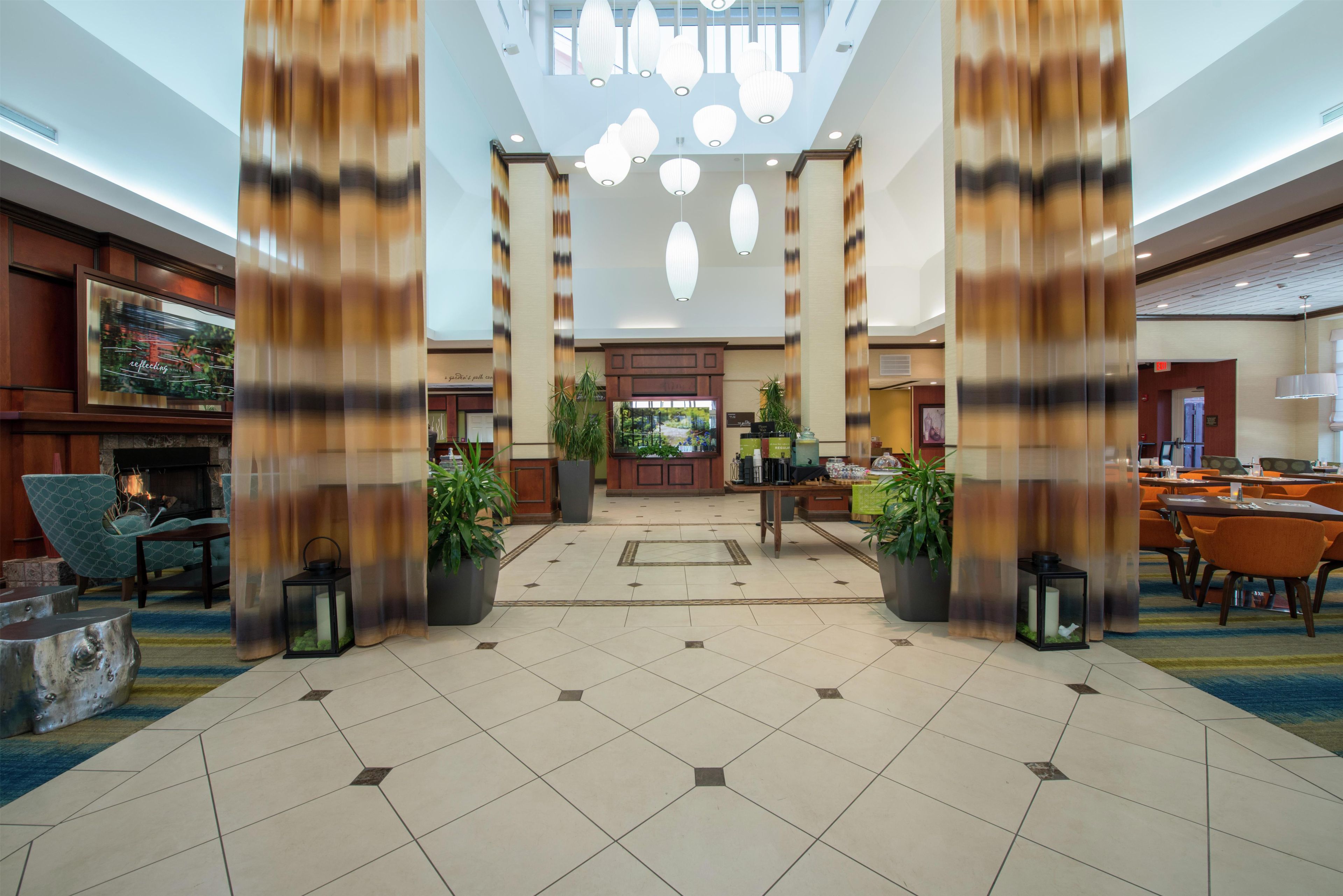 Un vestíbulo de hotel con mostrador de recepción, zona de estar y vistas al exterior.